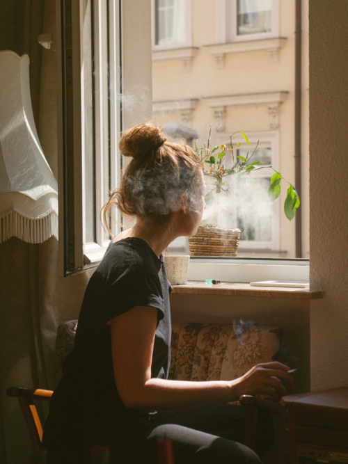 girl smoking looking out window